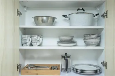 a pantry with plates and a pot and dishes at Julias Contemporary Apt Balcony and Golf View in Manila