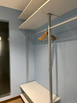 a room with white walls and a closet with shelves at Solace Hotel in Manila