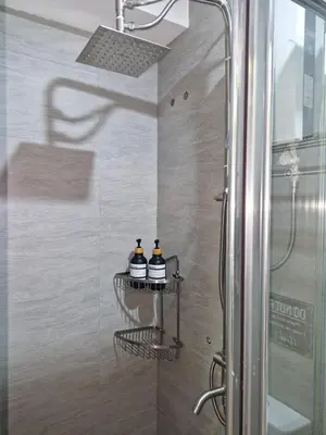a bathroom with a shower with two bottles at Comfy Stay 50 mbps Wi-Fi, Smart TV, Netflix in Manila