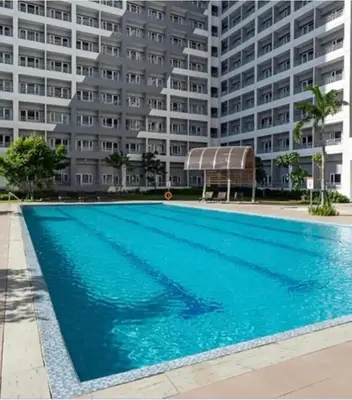 a swimming pool in front of a large building at Comfy Stay 50 mbps Wi-Fi, Smart TV, Netflix in Manila