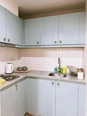 a kitchen with white cabinets and a sink at Chelsea Tower by Calvin in Manila