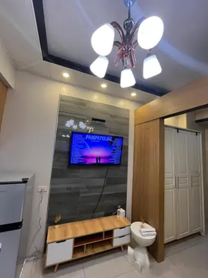a bathroom with a toilet and a tv on the wall at RJ Shell Staycation -PD in Manila