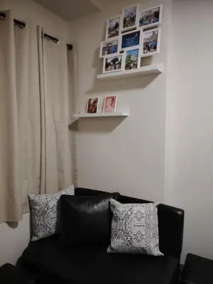 a black couch in a living room with pictures on the wall at 2BR Mountain View Condo SMDC Charm Metro Manila in Manila
