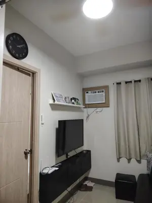 a room with a television and a clock on the wall at 2BR Mountain View Condo SMDC Charm Metro Manila in Manila