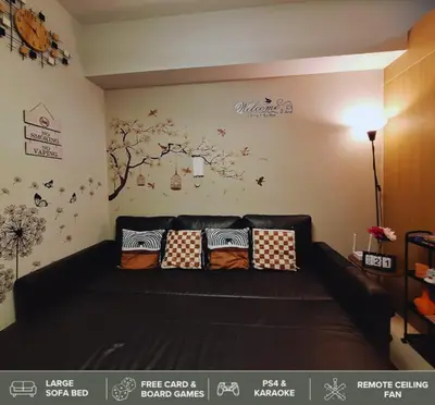 a living room with a black couch with pillows at Shore Residences - Near Mall of Asia in Manila