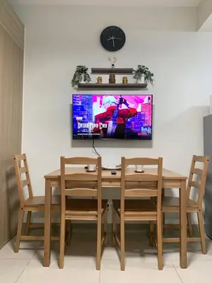 a dining room table with two chairs and a tv on the wall at Olivia in Manila
