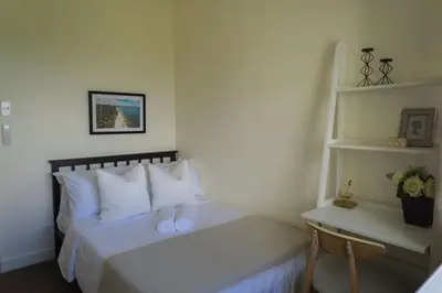 a bedroom with a bed with white pillows and a desk at Elegant and Modern 2 BR Home Golf Skyline View in Manila