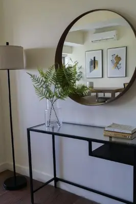 a mirror on a wall above a table with a plant at Elegant and Modern 2 BR Home Golf Skyline View in Manila