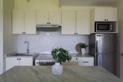 a kitchen with white cabinets and a vase with a plant at Elegant and Modern 2 BR Home Golf Skyline View in Manila