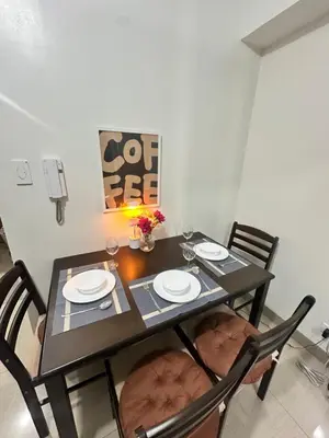 a dining room table with four chairs and a black table with plates at The Hideout Condotel in Shore 2 Residences Tower 3 in Manila