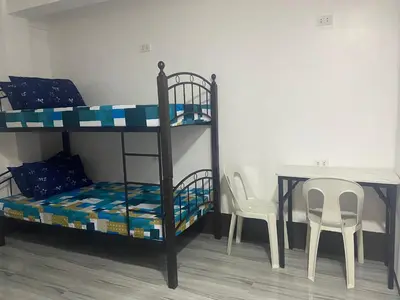 a room with two bunk beds and a table and chairs at Marites Guesthouse in General Trias