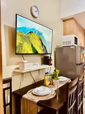 a kitchen with a table and a television on the wall at Azure Staycation - Pablo's Suites in Manila