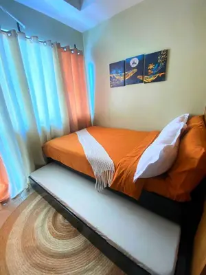 a bedroom with a bed with orange sheets and curtains at Azure Staycation - Pablo's Suites in Manila