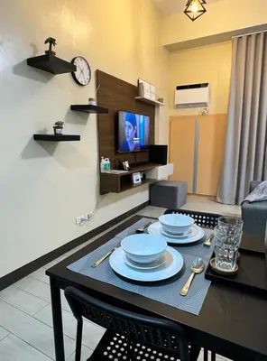 a living room with a table with plates and a tv at Cozy Haven - Newport - Walking distance to NAIA T3 in Sampong
