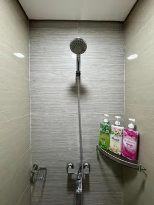 a shower in a bathroom with two shelves at Cozy Haven - Newport - Walking distance to NAIA T3 in Sampong
