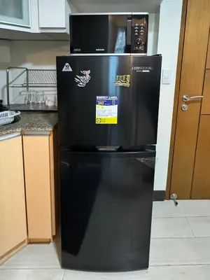 a black refrigerator with stickers on it in a kitchen at Cozy Haven - Newport - Walking distance to NAIA T3 in Sampong