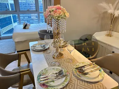 a dining room table with plates and a vase of flowers at Luxurious & Elegant Unit in Parksuites BGC in Manila