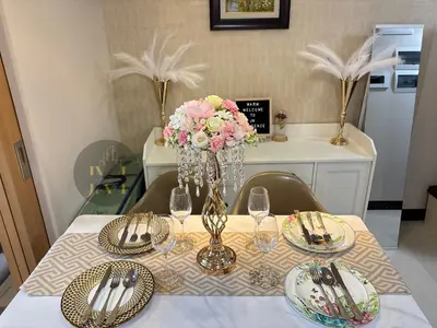 a table with plates and glasses and a vase with flowers at Luxurious & Elegant Unit in Parksuites BGC in Manila