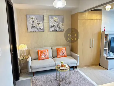a living room with a couch and two orange pillows at Luxurious & Elegant Unit in Parksuites BGC in Manila