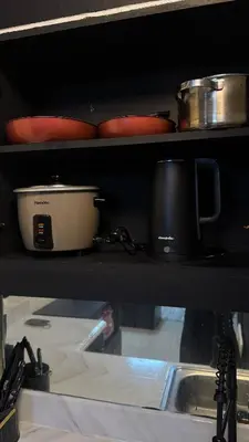a kitchen shelf with pots and pans and a sink at The Monochrome Nest in Manila