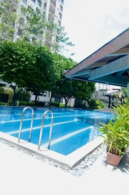 a swimming pool with two white chairs next to a building at The Monochrome Nest in Manila