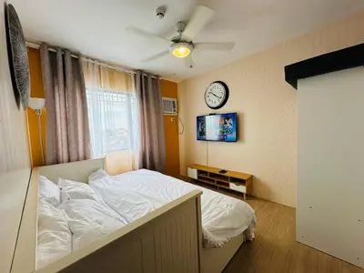 a bedroom with a bed and a clock on the wall at The Hive Condo Staycation Condo at Taytay Rizal in Taytay