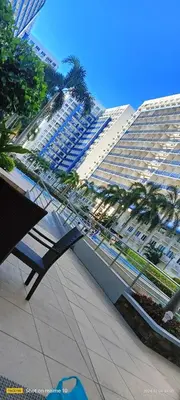 a bench in front of a large building with palm trees at Sea Residences LJ Place in Manila