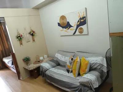 a living room with a gray bed with yellow pillows at Sea Residences LJ Place in Manila