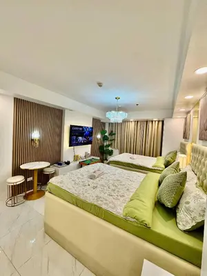 a bedroom with two beds and a flat screen tv at 1BR Bahamas 19th floor, Azure Paraaque in Manila