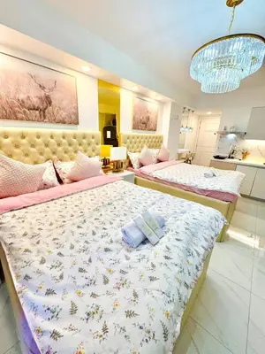 a bedroom with two beds and a chandelier at 1BR Bahamas 19th floor, Azure Paraaque in Manila