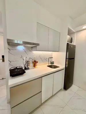 a white kitchen with a sink and a refrigerator at 1BR Bahamas 19th floor, Azure Paraaque in Manila