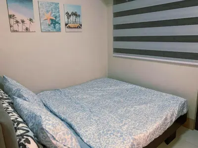 a bed with a blue comforter in a room at Minimalist Big 1BR Pool View MOA Airport in Manila