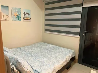 a small bedroom with a bed and a striped wall at Minimalist Big 1BR Pool View MOA Airport in Manila