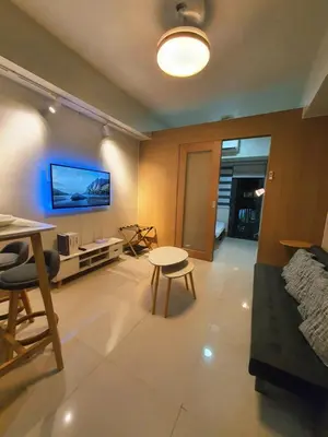 a living room with a bed and a table at Minimalist Big 1BR Pool View MOA Airport in Manila