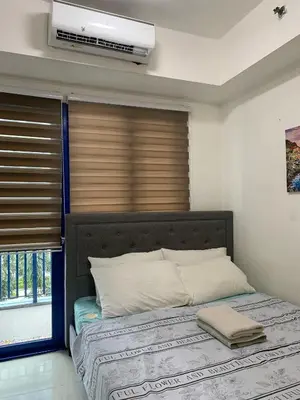 a bedroom with a bed and a window with a fan at Sea Residences by Estelle in Manila