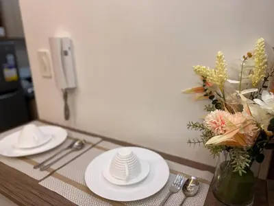 a table with white plates and a vase of flowers at Classy Spacious flat Shore2 Mall of Asia Pasay in Manila