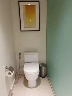a bathroom with a toilet with a picture on the wall at Novotel Hotel Residences at Acqua- AMOREsuite in Manila