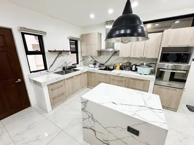 a kitchen with a marble counter top and a sink at Halika Villa & Capitolo events place near BGC in Manila