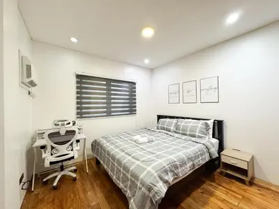 a bedroom with a bed and a desk and a window at Halika Villa & Capitolo events place near BGC in Manila