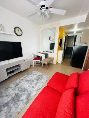 a living room with a red couch and a tv at Tower C 3rd Floor in Taytay