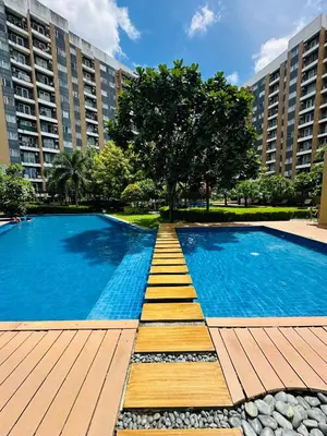 a swimming pool with a wooden walkway in front of a building at Tower C 3rd Floor in Taytay