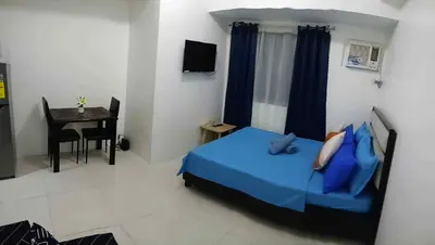 a bedroom with a bed with blue pillows and a desk at Tabatina Grand Reviera Suites in Manila