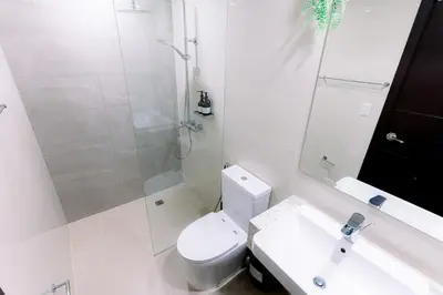 a bathroom with a toilet and a shower and a sink at Cozy 1BR Condo in McKinley West in Manila