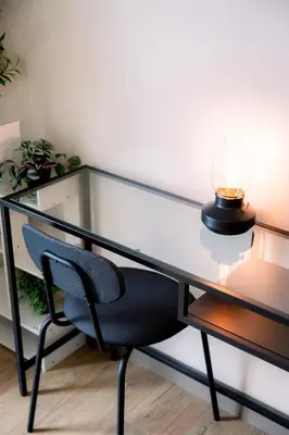 a glass desk with a chair and a lamp at Cozy 1BR Condo in McKinley West in Manila