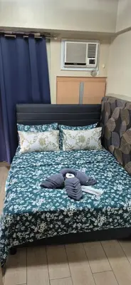 a bed with clothes on it in a room at Rqui Condotel Rooms Near Airports and Newport World Casino in Manila