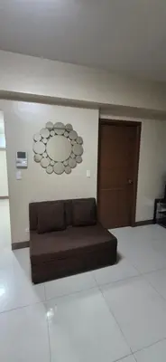 a brown couch in a room with a door at Rqui Condotel Rooms Near Airports and Newport World Casino in Manila