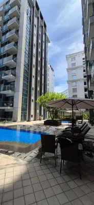 a table with an umbrella and chairs next to some buildings at Rqui Condotel Rooms Near Airports and Newport World Casino in Manila