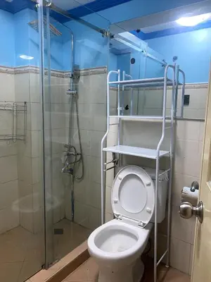 a bathroom with a toilet and a glass shower at The Blue Unit - By H&A in Manila