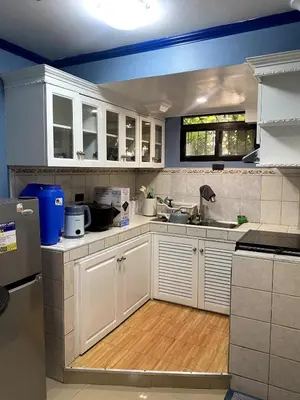 a kitchen with white cabinets and a wooden floor at The Blue Unit - By H&A in Manila