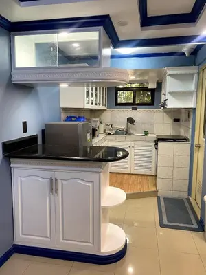 a kitchen with white cabinets and a black counter top at The Blue Unit - By H&A in Manila